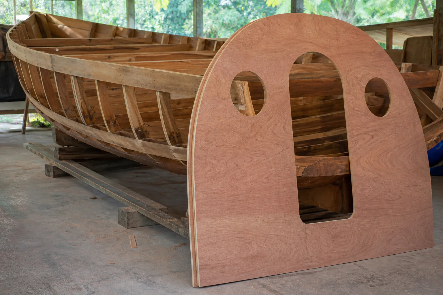Curved plywood bulkhead template beside a timber boat frame.