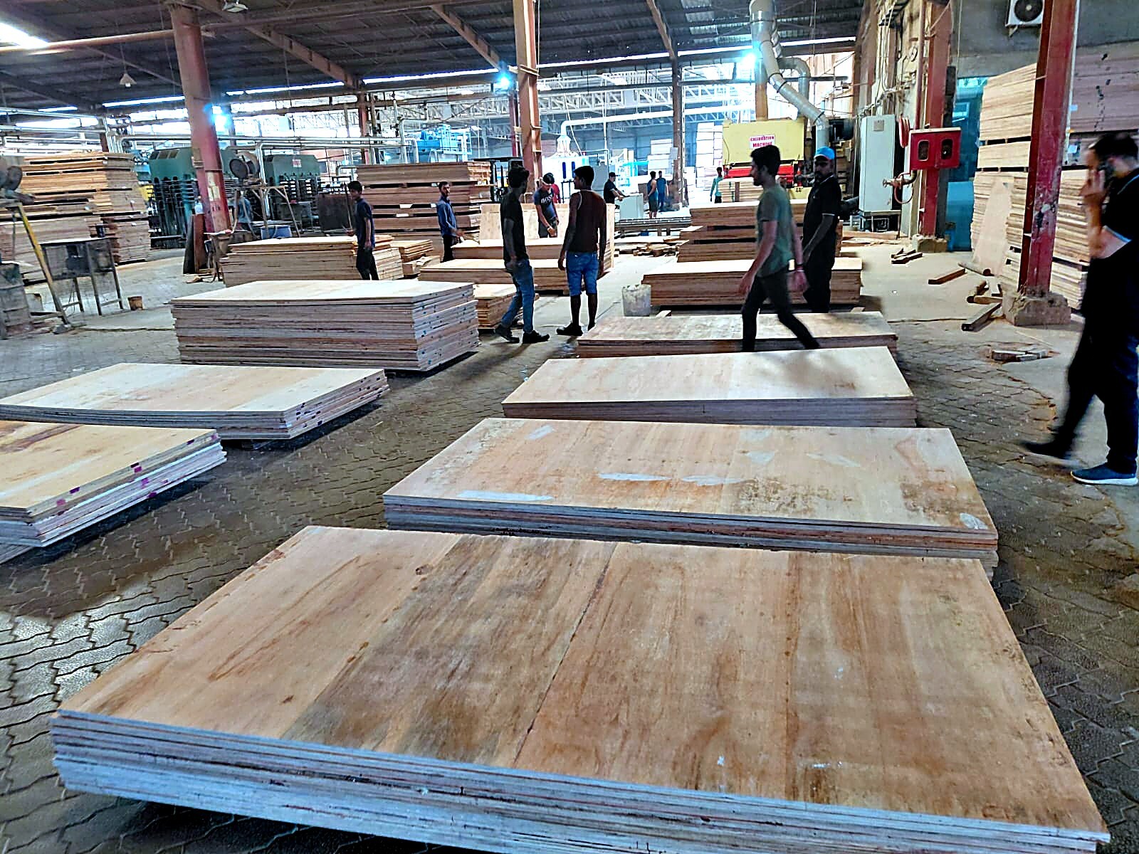 Workers handling plywood sheets on the floor