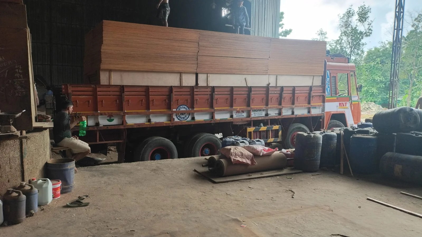 Stacks of plywood on a red lorry inside an industrial loading shed