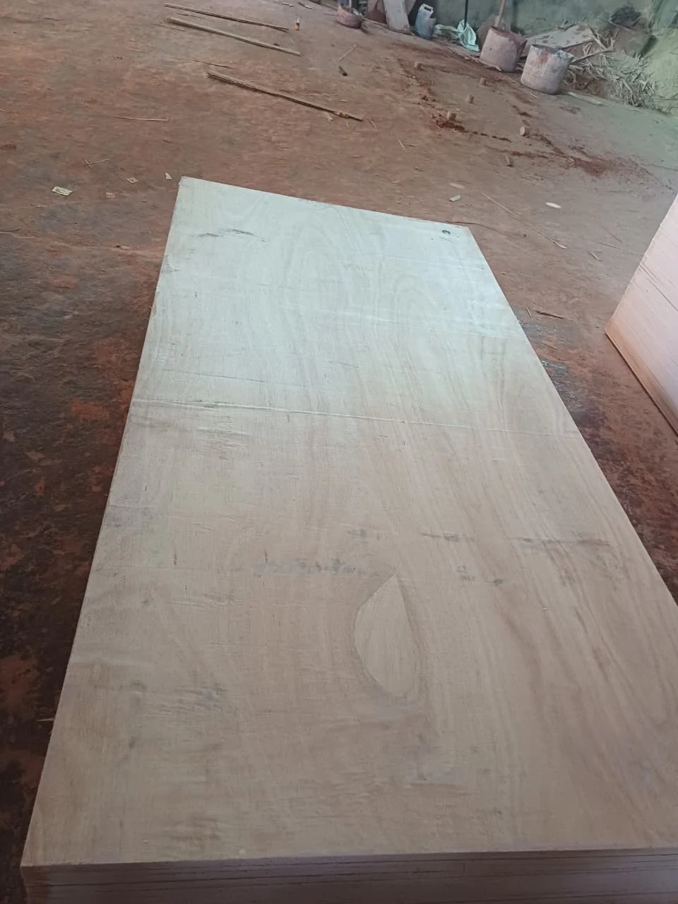 A pale plywood panel lying flat on a sheet stack in a workshop